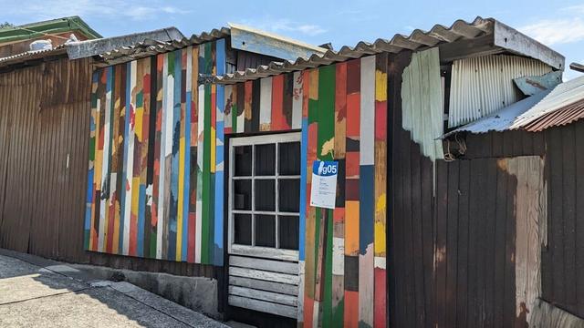 A work of art that consists of painted wooden panels on the wall of an old Japanese house. Each panel is different, with different colors and motifs.