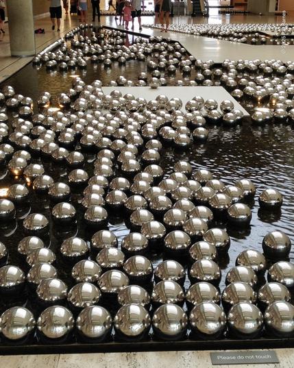 Internal pool in the Brisbane Art Gallery, almost completely filled with hundreds of shiny, floating chrome spheres, each about 20cm in diameter, each with a distorted reflection.