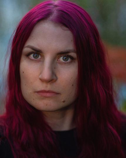 A closeup portrait of a red haired Finnish woman looking at camera