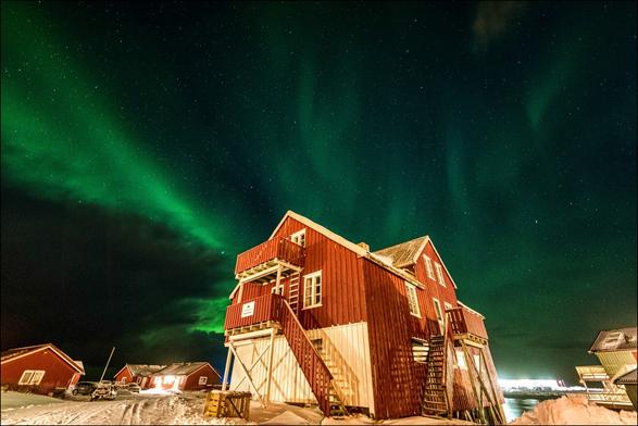 Nachtaufnahme eines nordischen Hauses mit Aussentreppen unter Polarlichtern.