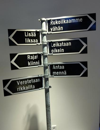 Liikennetolppa, jossa suuntamerkkejä 

Lisää liksaa 

Rajat kiinni 

Verotetaanrikkailta 

Rukoilkaamme vähän 

Leikataan oikein 

Antaa mennä 

Tolppa on Merkki-museossa.