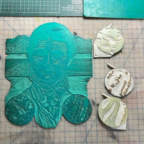4 carved lino blocks on top of cutting mats. The largest is a portrait of geologist Florence Bascom as a young woman from neck up, looking at the viewer with her curly hair pulled back wearing a blouse with large lace collar on green vinyl. Behind her are two geological cross-sections with layers carved with different patterns to indicate different rock materials. Below on either side are two circular diagrams: these are thin sections with the patterns of the darkest ares carved. The three other Lino blocks are circular with patterns carved to print the other mineral colours in the thin sections.