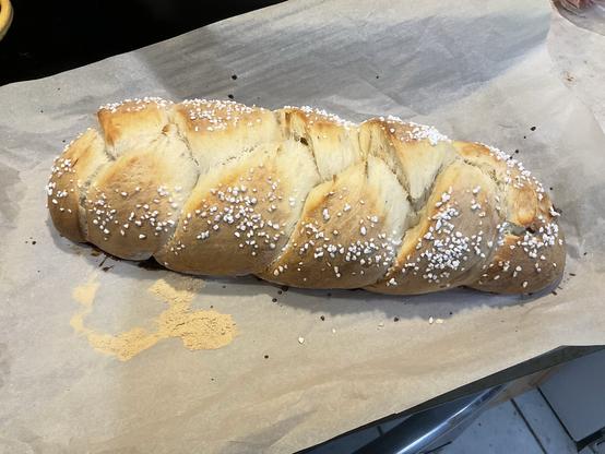 A braided loaf of sourdough bread in a pan lined with parchment paper. It is a sweet bread seasoned with cardamom, and topped with pearl sugar.
If you are Finnish, this is pulla, and you have it with a nice cup of coffee.