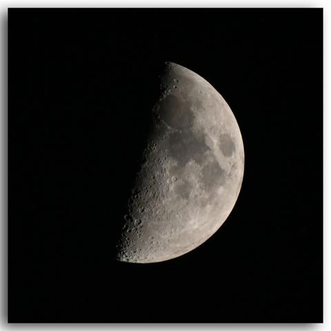 Der unwesentlich mehr als halbe, zunehmende Mond recht detailreich vor annähernd schwarz wirkendem Himmel.