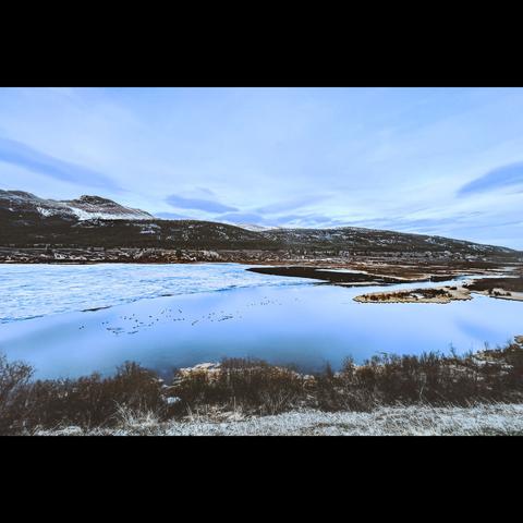 Landscape photo in color, from British Columbia in Canada.Ths is a lake with ice, with the sky reflection