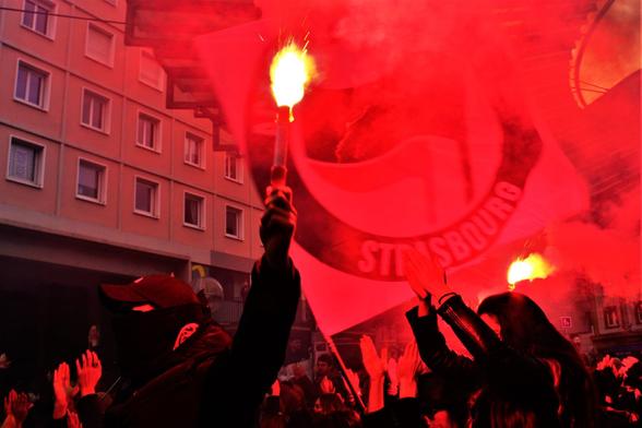 Des manifestant•es avec des fumigènes rouges