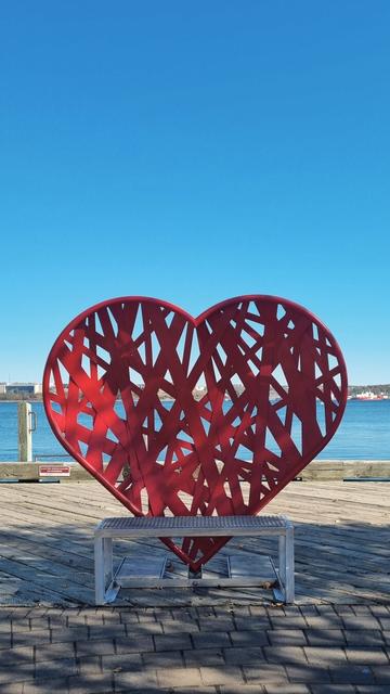 Bench with the back made like a giant red heart is overlooking the harbour.