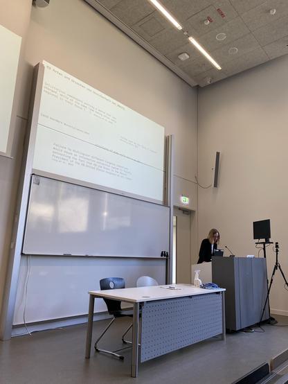 Sophie Schneider vorn im Hörsaal beim Vortrag und Blick auf Präsentation