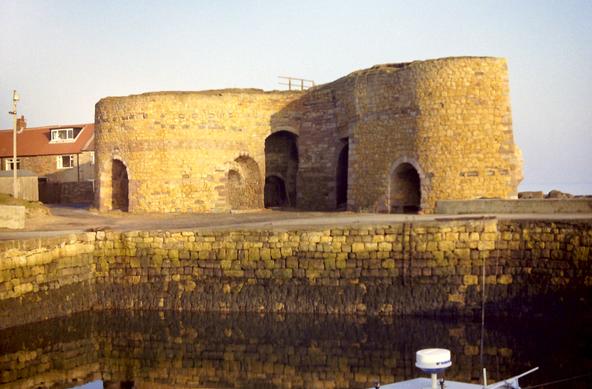 A group of brick-built cylindrical kilns, by the waterside.