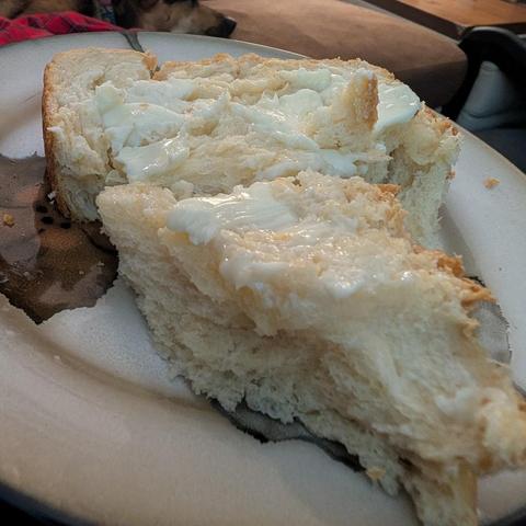 A hunk of freshly baked bread on a plate, with pats of butter melting on the top.