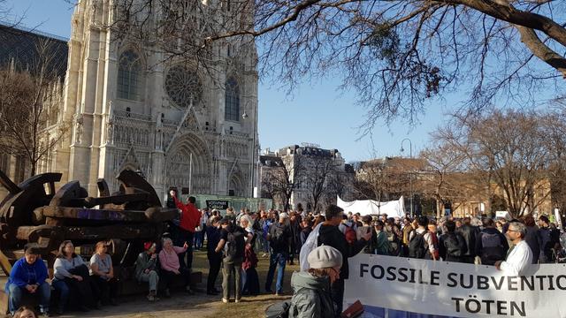 A crowd of people in Sigmund-Freud-Park next to Votiv Church, Vienna. Scientists hold a sign saying Fossile subventions kill