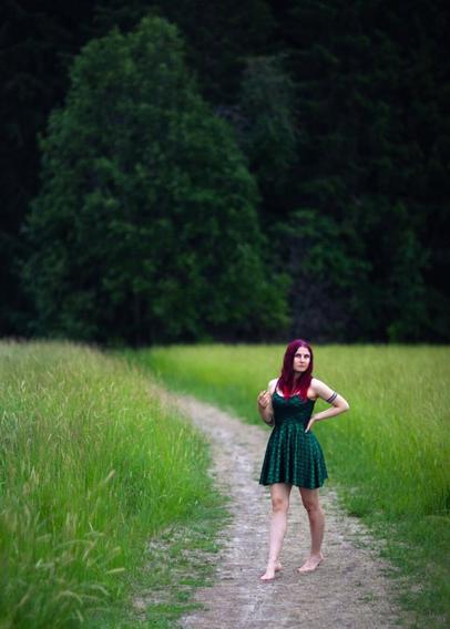Red haired woman with bruised knees and a mermaid dress walking barefeet in nature