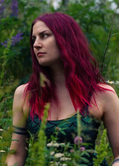 Portrait of a red haired woman with a serious expression in a field of flowers