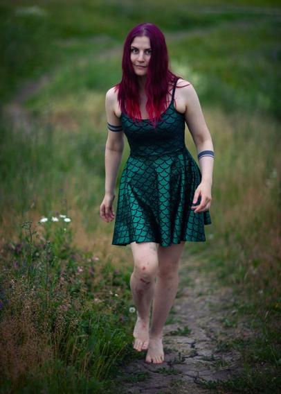 Red haired woman with bruised knees and a mermaid dress walking barefeet in nature