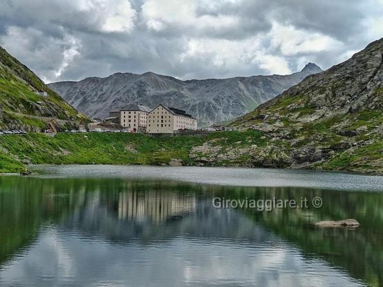 L'ospizio del Gran San Bernardo si riflette nelle acque del lago al passo omonimo. Il tutto circondato da montagne della valle d'Aosta