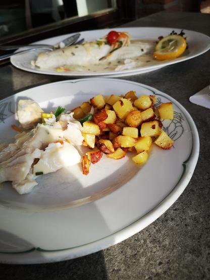Eine Servierplatte und ein Teller.
Darauf gedünsteter Zander und Bratkartoffeln.