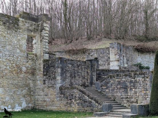 Escalier montant entre murs de vielles pierres et de ruines.