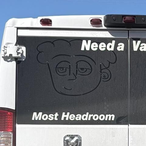 The (dirty) rear window of a rental van, where some drew a face on it