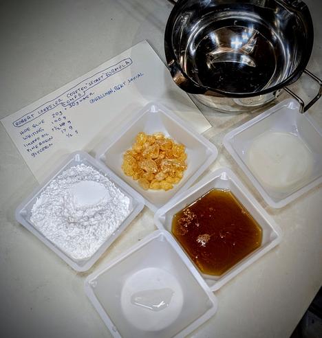 Measured out ingredients for a small experimental batch of Compo heat activated molding compound.  
It is 70% dry powder, gypsum, aka 'whiting'.
The 30% binder is thermally activated, half hide glue which melts at 160⁰F plus half pine rosin which melts at 185⁰F plus some linseed oil and a couple drops of vegetable glycerin. The recipe is taken from the ultra rare book by Robert Loeffler 'Compo A step by step guide'