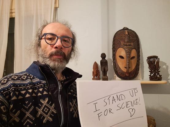 Me holding a sign "Stand up for Science" in my bedroom