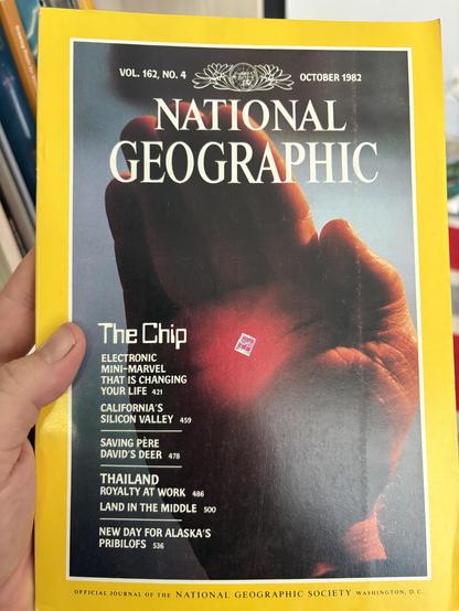Cover of an issue of National Geographic (Volume 162, no. 4; October 1982), featuring a hand holding a microchip with a list of other stories about microchips, Silicon Valley, saving deer in Père David, Thailand, and Alaska’s Pribilofs