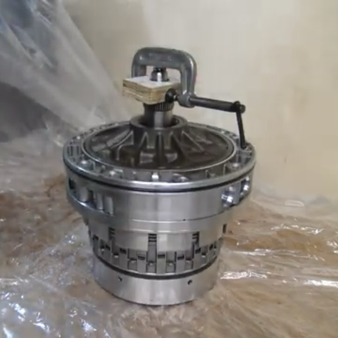Screenshot from a YouTube video showing how the two pieces of wood clamp onto the central spline of the clutch pack and oil pump assembly, allowing the clamp to be used as a handle to lower the parts into the transmission case standing on its end.
