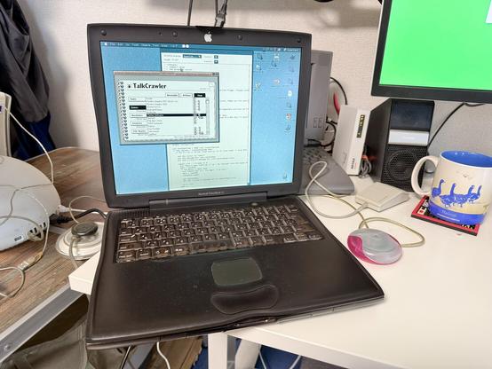 A PowerBook G3 Lombard with a pink puck mouse 

A PowerBook 540c is seen in the background 

Off the the left, on a shaky camping table, an iMac G4 can be spotted
