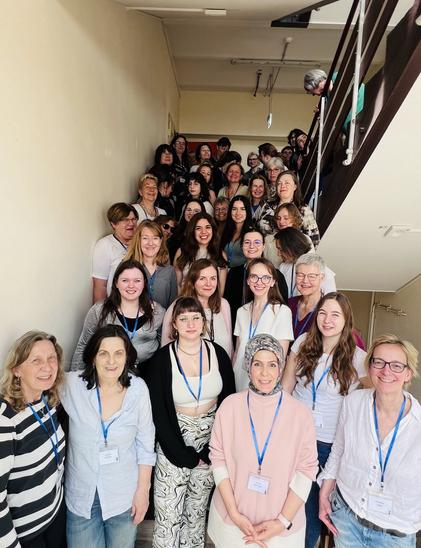 Gruppenbild von einem Treffen der Fachgruppe: In einem Treppenhaus haben sich ca. 30 Frauen aus der Informatik-Community versammelt. Sie tragen blaue Bändchen und lächeln.