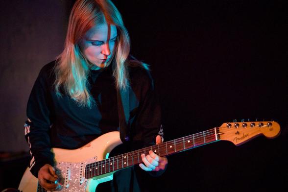 Eine Gitarristin mit blonden Haaren beim Gitarrenspiel.