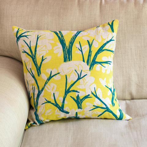 A hand printed cushion with trees in blue and yellow.