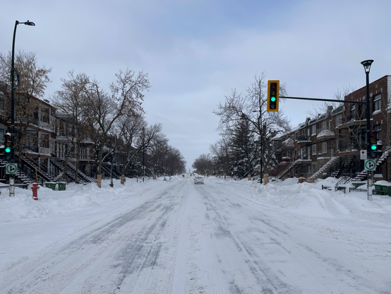 A large avenue in Montreal, shot from the middle of the pedestrian crosswalk, with green traffic lights.
