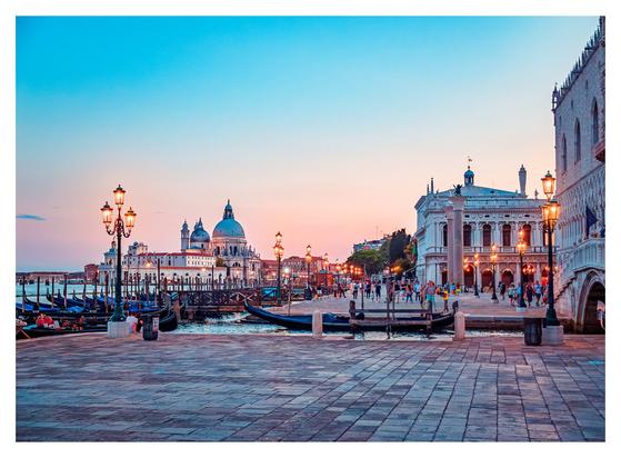 A serene evening in Venice, Italy, showcasing a sunset that casts warm hues over the iconic canals and architecture.