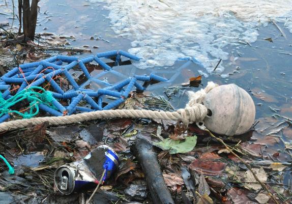 Ceramic buoy and ceramic fishing net on a muddy riverside surrounded by other wastes