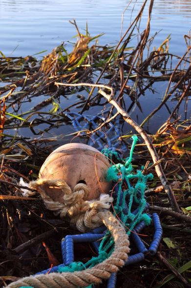 Ceramic buoy and ceramic fishing net on a riverside like a waste.
Mix-media sculpture project.