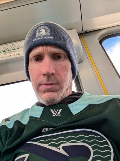 Scruffy Middle aged man, wearing a blue Boston Marathon hat, and pwhl jersey