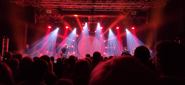 Pink Floyd Tribute Band »Kings of Floyd« in der Oldenburger Kulturetage. Bühne im rotem Licht, helle Strahler im Vordergrund.