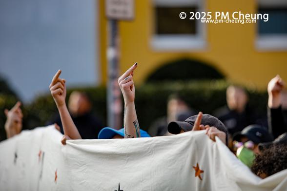 An der Demonstrationsspitze recken mehrere Demonstrant*innen den vorderen FLINTA*Block ihre Hände in den Himmel und zeigen den Mittelfinger.