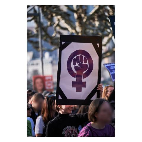 Foto: Mensch hält Demonstrationsschild hoch mit dem Zeichen für Feminismus
