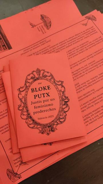 foto de papeles rojos con texto en negro donde se lee una portada que dice 8M BLOKE PUTX Juntis por un feminismo proderechos Valencia 2025, detrás el manifiesto mencionado en la publicación.