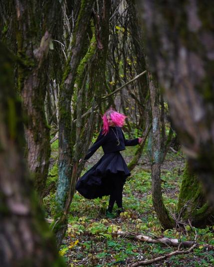 Pink haired woman dancing in an autumn forest