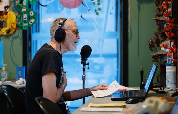 A man wearing headphones holds a hand to his chest