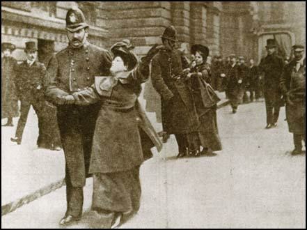 newspaper photo of Flora Drummond and Annie Kenney being frog marched away from Number 10. Flora is in the foreground, and only comes to the shoulder of the policeman arresting her. Both women are white.