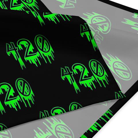 A closeup of the corner of a black bandana with the number 420 in a repeating pattern. The numbers are neon green with a purple outline in a creepy, dripping font.