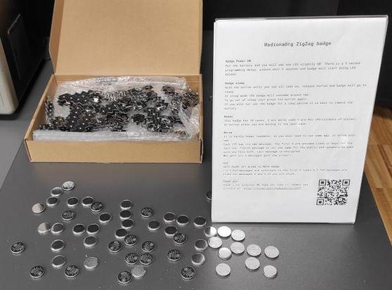 Batch of badges and batteries on table with instructions for task (available on second link)