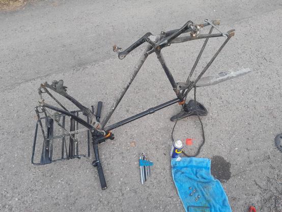 Black Surly Steamroller fixed gear frame without wheels upside down. Tools on the ground.