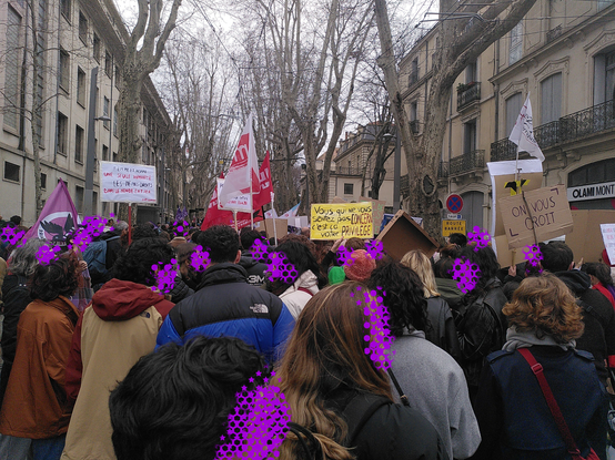 Encore des dizaines de personnes qui manifestent, vues de dos. Il y a encore des drapeaux et des pancartes.

"femme et homme, une seule humanité, les mêmes droits dans le monde entier"
"Vous qui ne vous sentez pas concerné, c'est ça votre privilège"
"On vous croît"