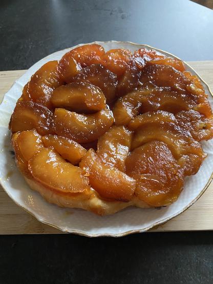 French Apple desert Tarte tatin on a plate. The apples are brown in colour and are visible on top of the tart.