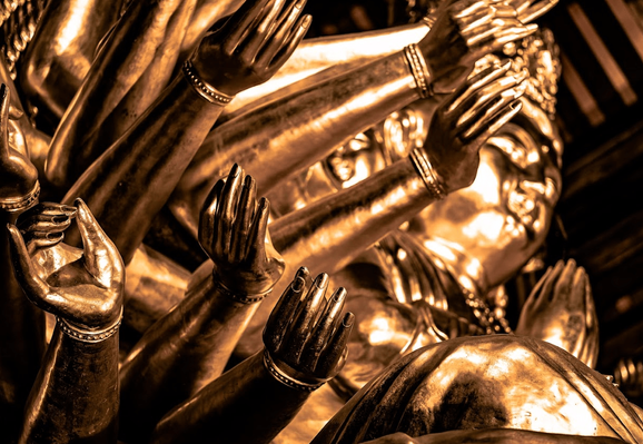 A gold statue of a Buddhist deity with multiple arms encasing a half smiling face.