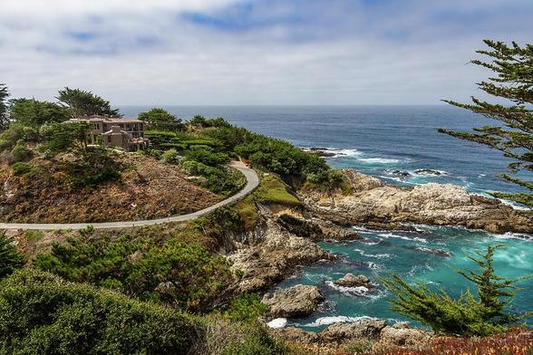 Stunning view of the Pacific Ocean from Carmel Highlands Vista Point, California, showcasing rugged cliffs, blue waters, and lush greenery.
