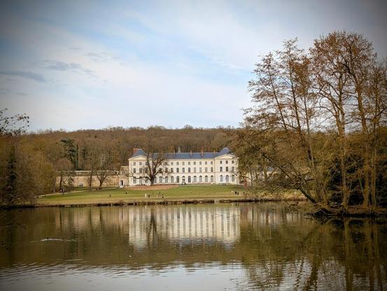 Un château d'architecture classique de style Louis XVI (fin 18e) devant une pièce d'eau.